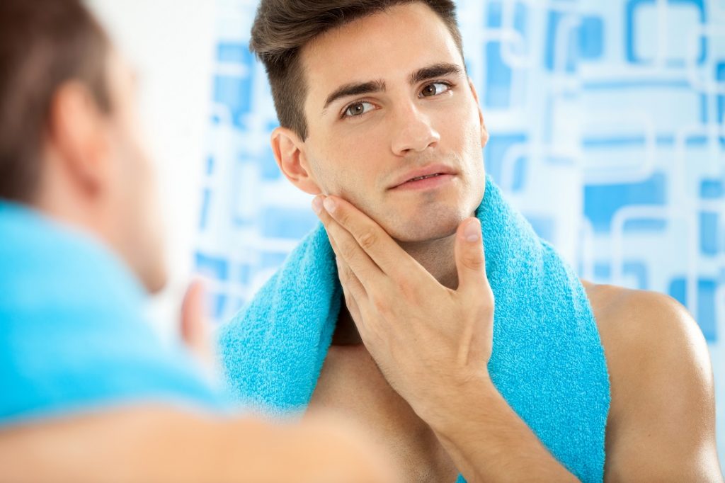 Young handsome man touching his smooth face after shaving